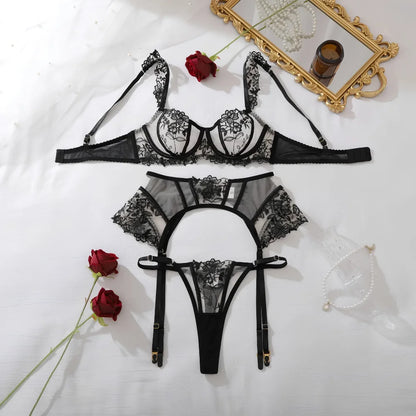 Black floral lace lingerie set laid flat: bra, garter belt, and thong